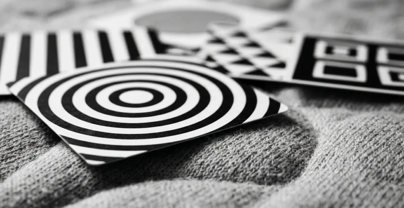 Cartes de stimulation visuelle en noir et blanc avec motifs géométriques contrastés disposées sur un tapis d'éveil